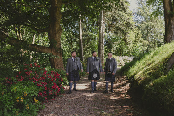 Groom and his groomsmen walk in woodlands at Norwood Hall Hotel